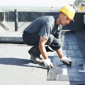 ouvrier qui pose un revêtement sur un toit